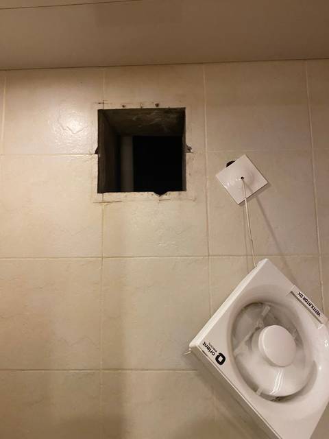       A wall with a ventilation hole and fan installation.
  