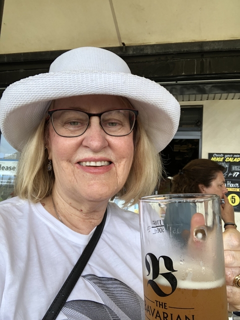 A person smiling and holding a glass in a restaurant setting.