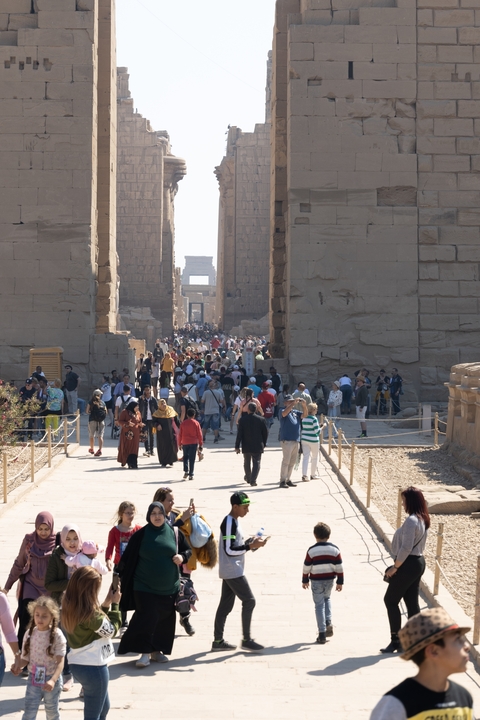 Crowds walking through the ruins of an ancient Egyptian complex.