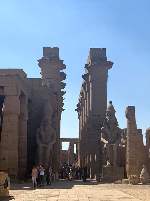 Ancient statues and ruins under a clear blue sky.