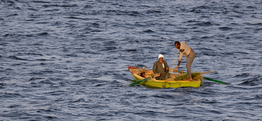      Two people in a small boat on a river.
  