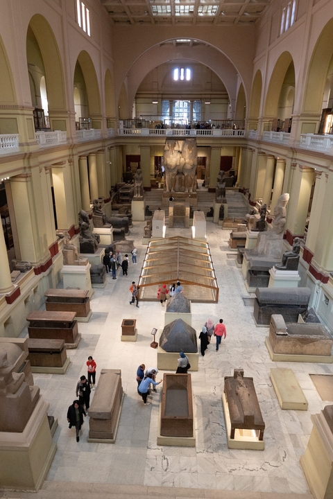 Interior of an Egyptian museum with artifacts and visitors.