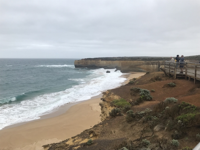 A coastal landscape with a sandy beach and cliffs.
