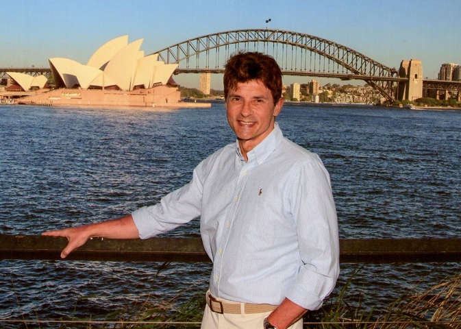 A person standing in front of Sydney Opera House and Sydney Harbour Bridge.