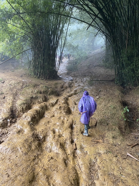 Person walking on a muddy trail in the rain.