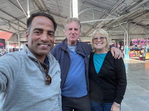       Three people posing indoors under a ceiling structure.
  