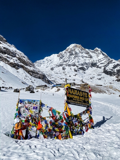       Annapurna Base Camp in the snow with colorful flags.
  