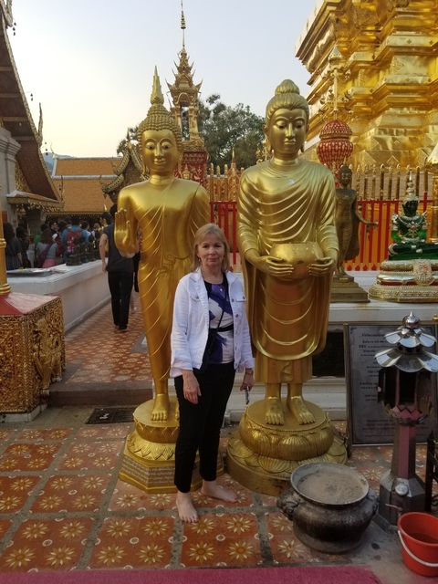 Woman standing between golden statues at a temple.
