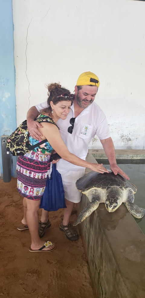       Couple posing with a turtle indoors.
  