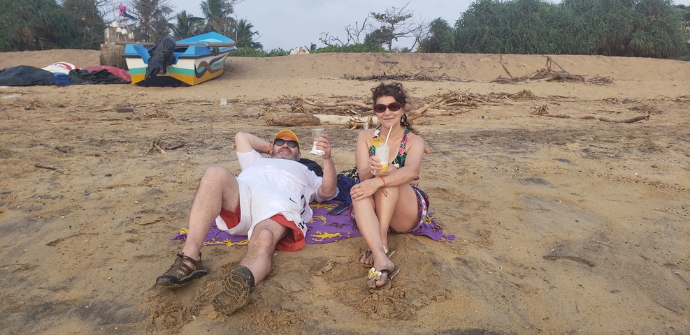       Couple relaxing on a beach with drinks.
  