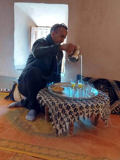 A person pouring tea seated indoors.