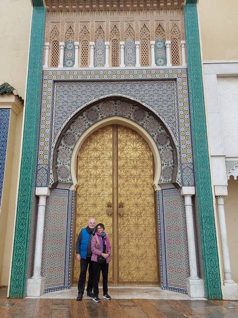 Two people standing in front of a beautifully decorated door.