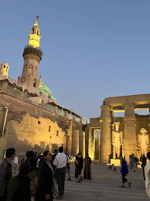 Tourists amid ancient ruins under a twilight sky.