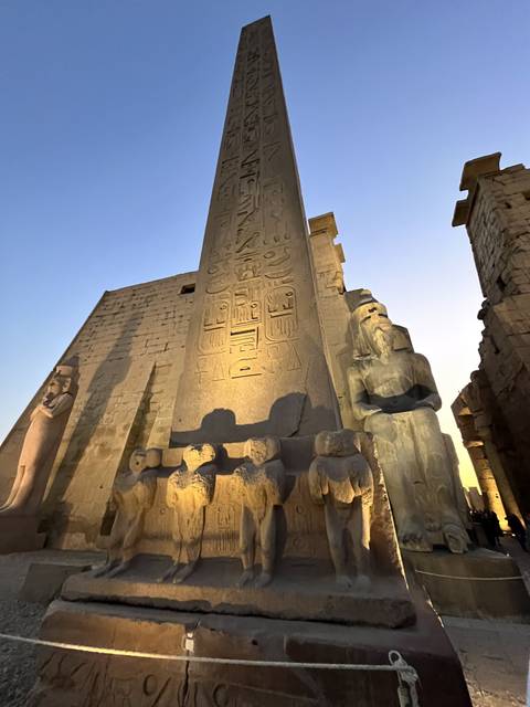 Ancient Egyptian obelisk with hieroglyphics lit by soft lighting.