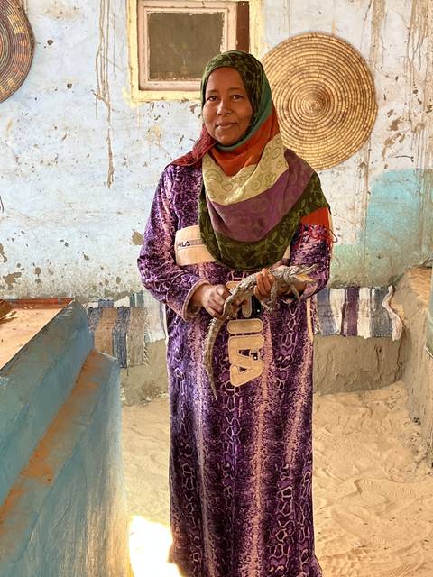Woman in traditional attire holding a small crocodile.