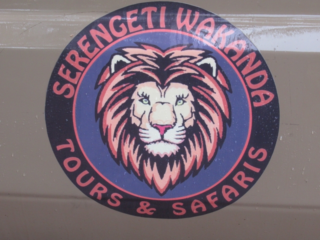       Close-up of a logo for Serengeti Tours on a vehicle.
  