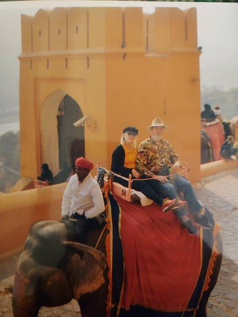       People on elephants in a traditional setting.
  