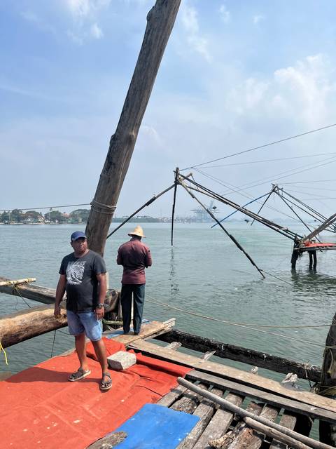 Two men overlooking a water body with fishing nets.