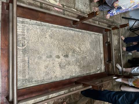       People standing around a slab with impressions.
  