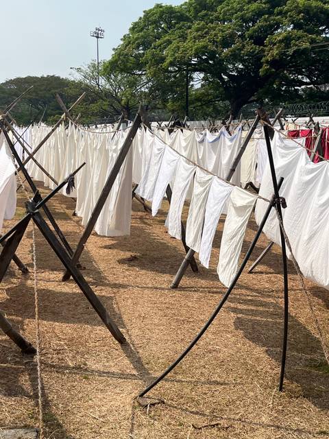       Clothes hanging on drying racks in a field.
  