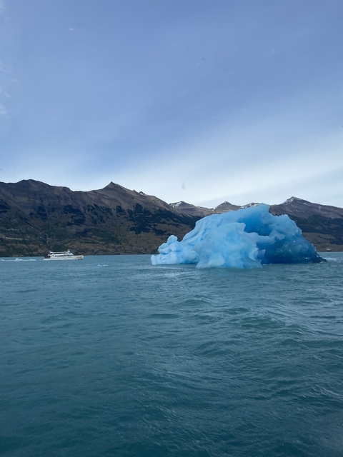 Single iceberg floating near a boat in icy waters.