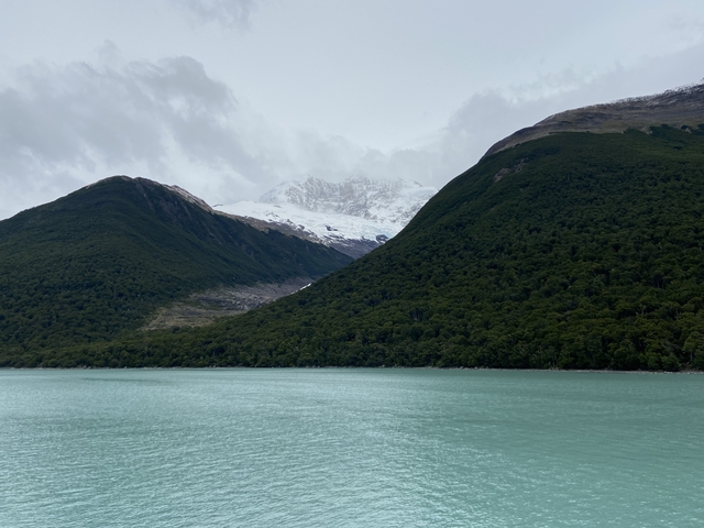       Forest-covered mountains with a snowy peak.
  