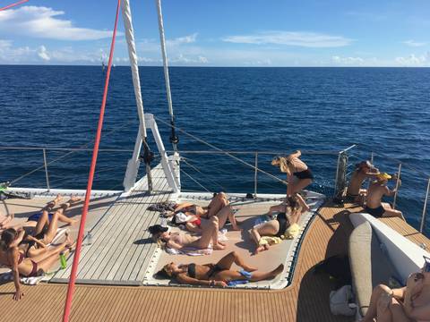       People sunbathing on a sailboat.
  