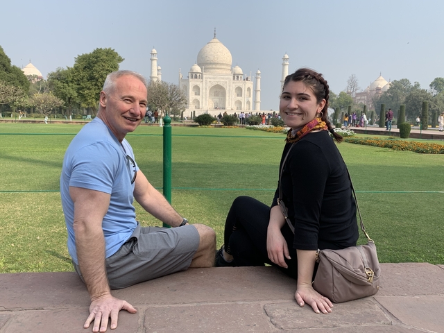 Two people sitting with the Taj Mahal in the background.