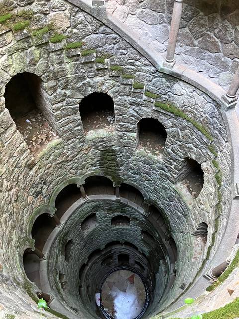 A spiral staircase descending into a stone well.