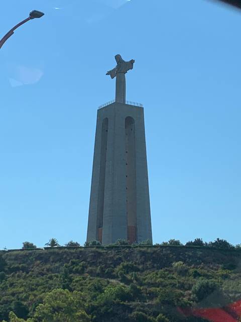       Tall statue on a pedestal with an open arms gesture.
  