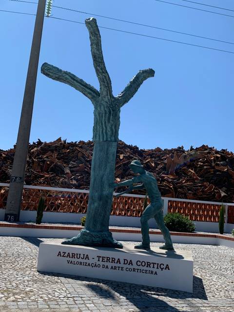       Metallic statue of a man with a tree in an industrial setting.
  