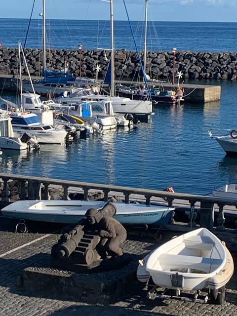 Small harbor with boats moored and a stone pier.