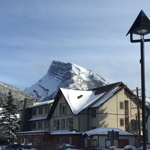       Snowy mountain peak with buildings in foreground.
  