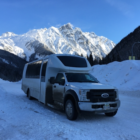       Bus parked in front of a scenic snowy mountain.
  