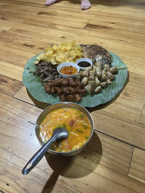 Platter of assorted Vietnamese dishes, served on a large leaf with a bowl of soup.