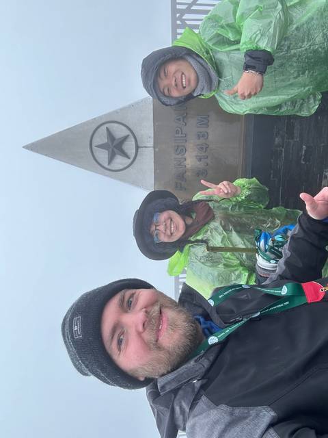       Three people pointing at a sign with a star.
  