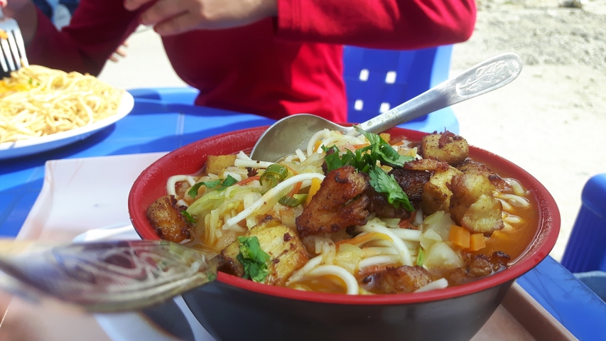       Bowl of noodle soup with assorted vegetables and chicken.
  