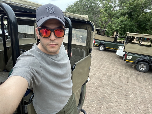 Person standing next to safari vehicles.