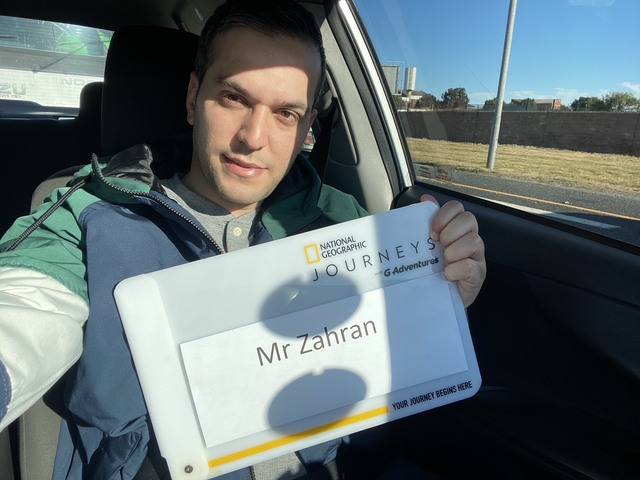 Person holding a sign while sitting inside a car.