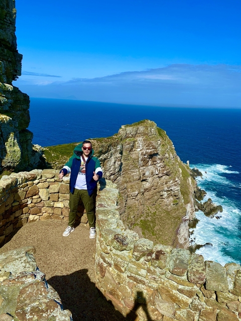 Person standing on a rocky viewpoint overlooking the ocean.
