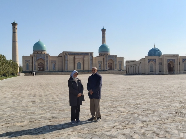 Two people standing in front of a historical building with large domes.