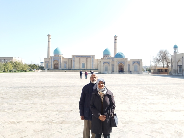 People posing in front of a historical building with large domes.