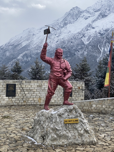 Statue of a man with a mountainous backdrop.