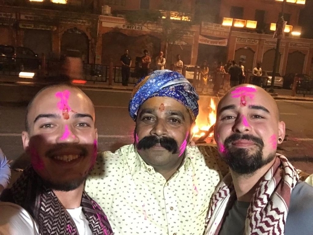 Three men with painted faces celebrating near a fire.