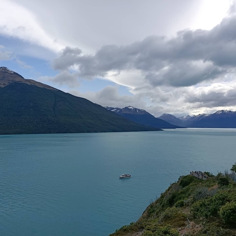 Lake with mountainous landscape under a cloudy sky.
