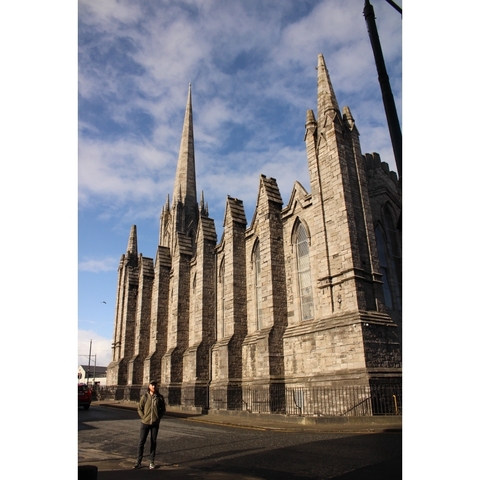 Stone cathedral with large spire against a blue sky.
