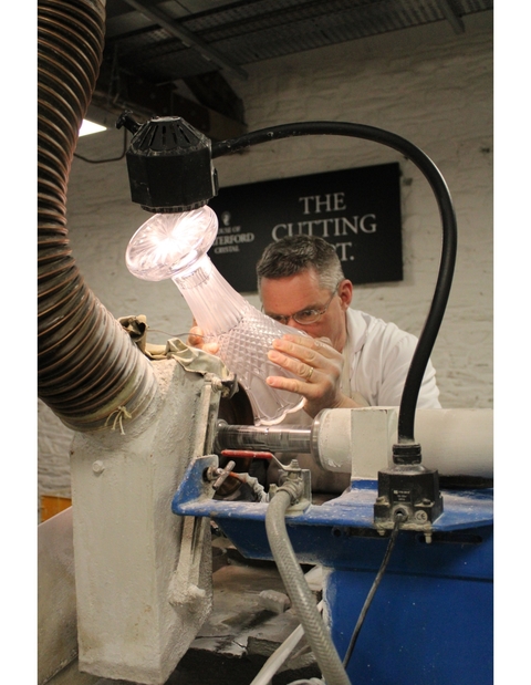 Craftsman working on a glass vase in a workshop.