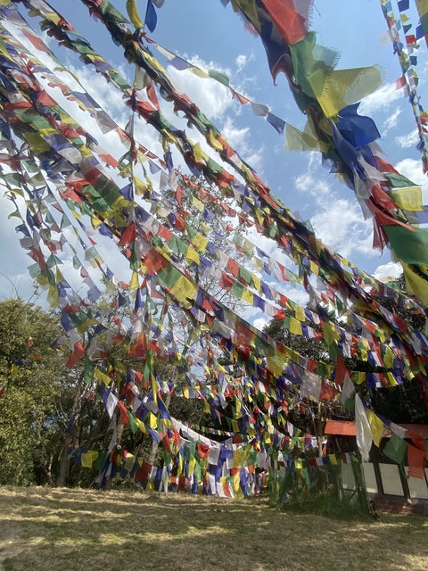 Colorful prayer flags strung up with a blue sky background.
