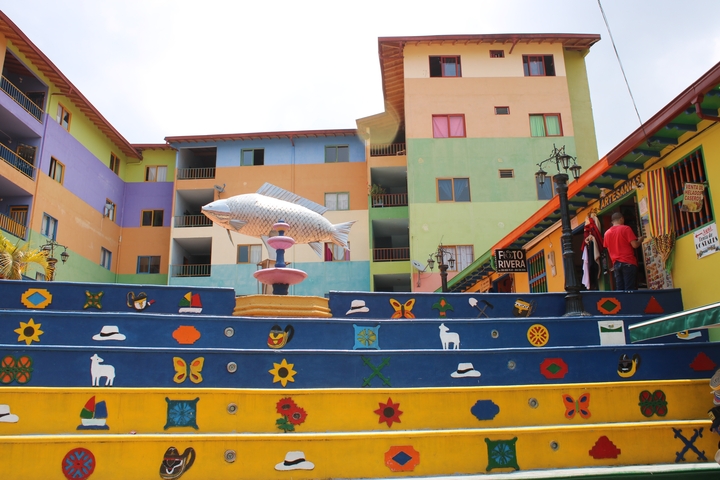       A colorful staircase with a large fish sculpture and multi-colored buildings.
  