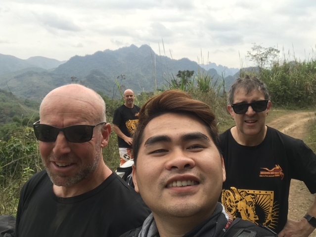 A group of people taking a selfie with a mountainous backdrop.